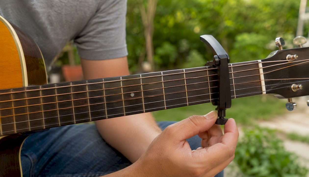 Met de hand de spanning van de capo op de gitaar afstellen.