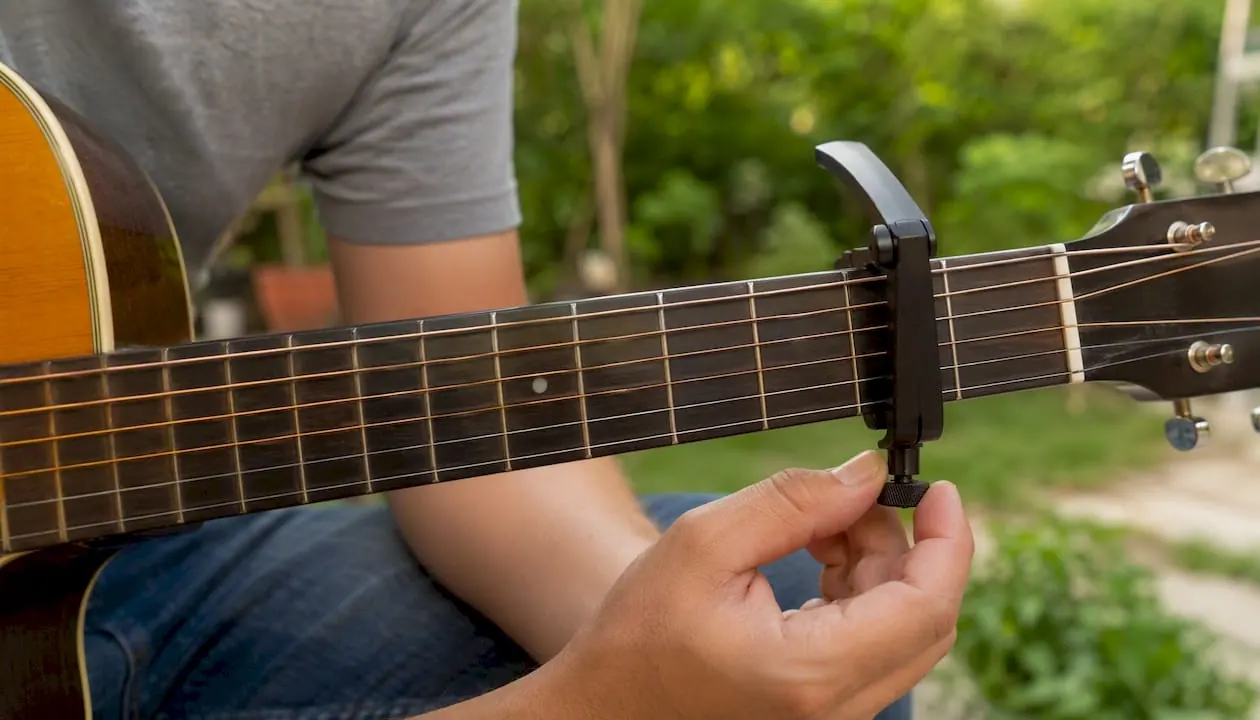 Met de hand de spanning van de capo op de gitaar afstellen.