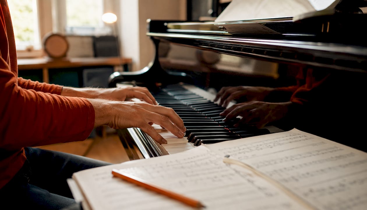 Een close-up van vingers die soepele jazzakkoorden op de piano spelen.
