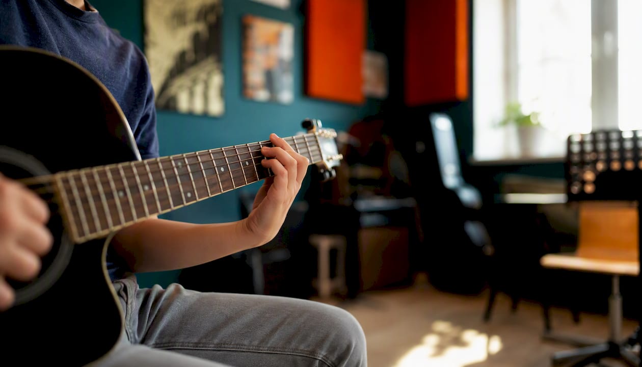 Een kind zit gezellig in de buurt gitaar te spelen.