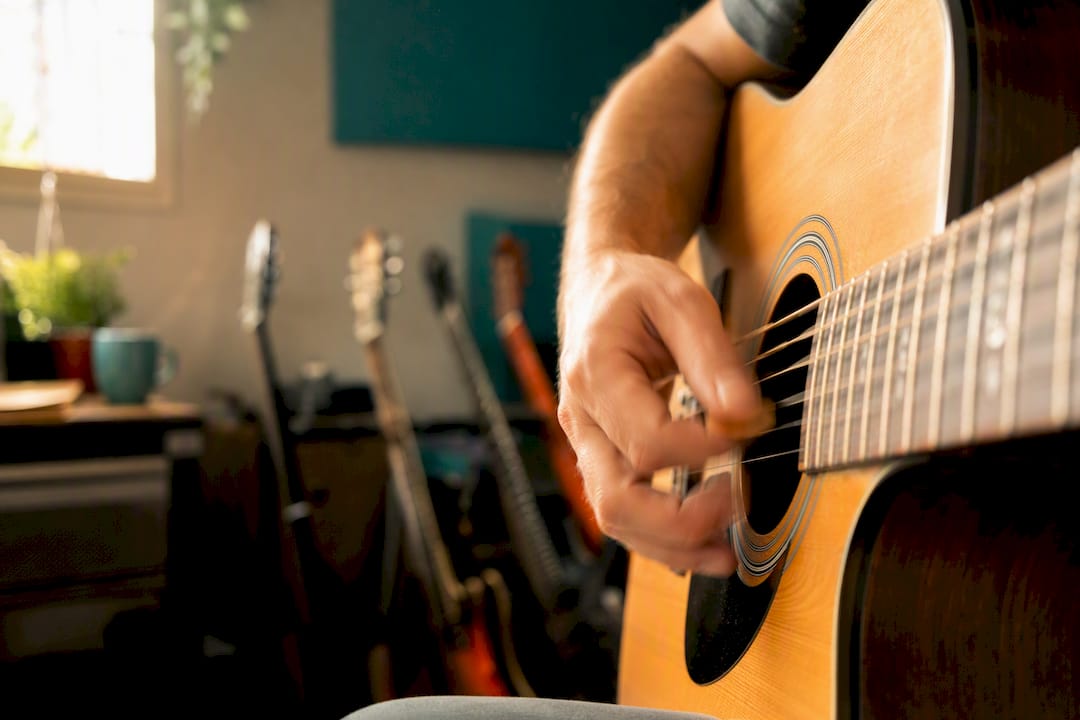 Hand die met een plectrum over gitaarsnaren strumt
