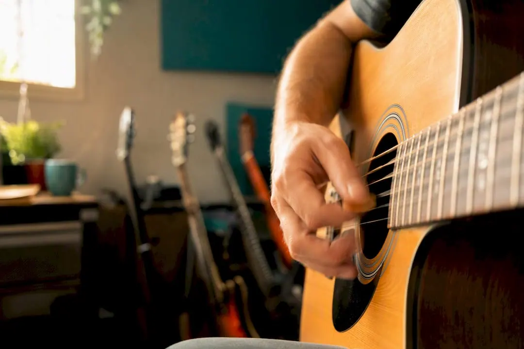 Hand die met een plectrum over gitaarsnaren strumt