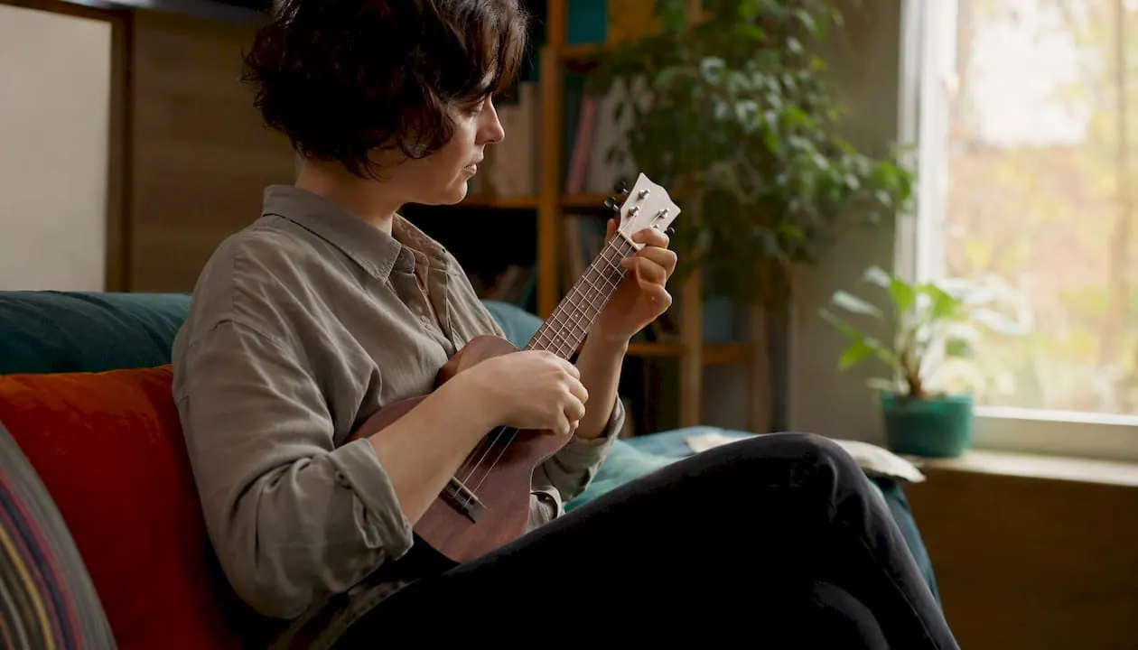 Een beginner die thuis op een sopraan ukelele speelt